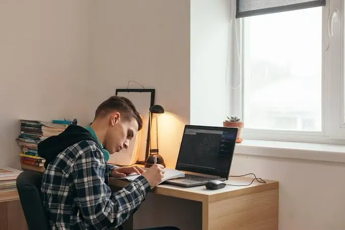 Un joven estudiando en calma gracias a ventanas de PVC blancas con aislamiento acústico. Máxima concentración sin ruidos molestos.